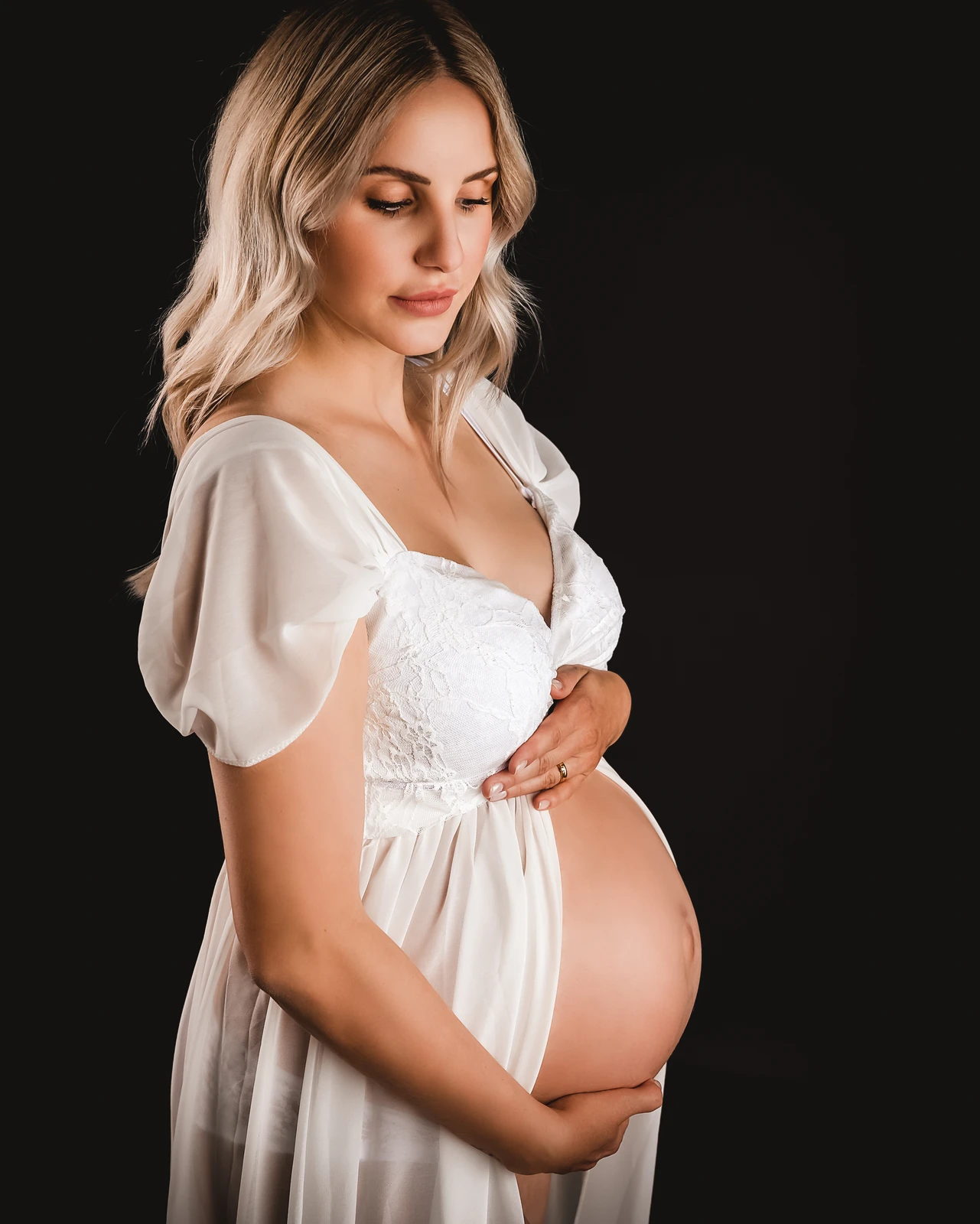 Schwangerschaftsfoto- schwangere umfasst ihren Bauch und schaut ihn an-luzern